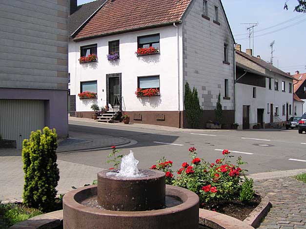 Der Dorfbrunnen in Schallodenbach mit Haus Hemmer in der Großen Gasse